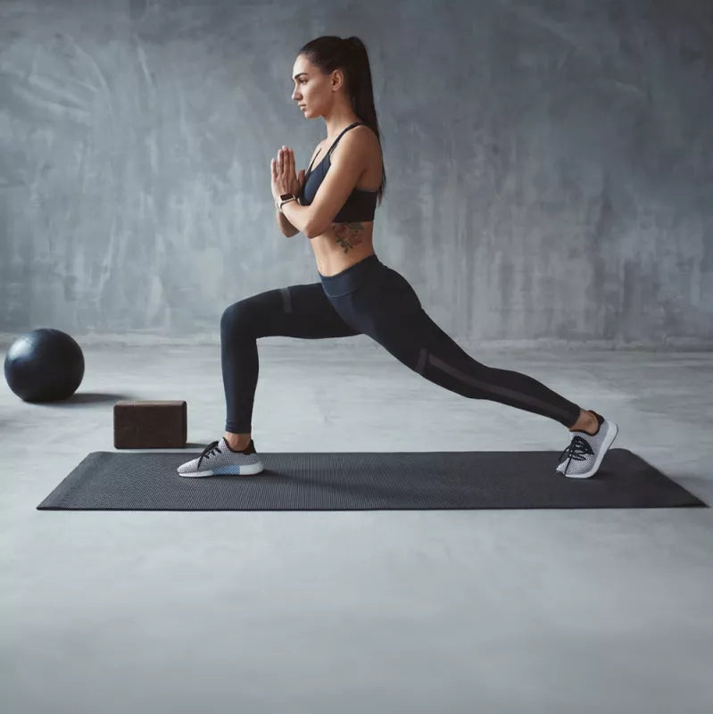 Woman exercising in a lunge on a black gym mat